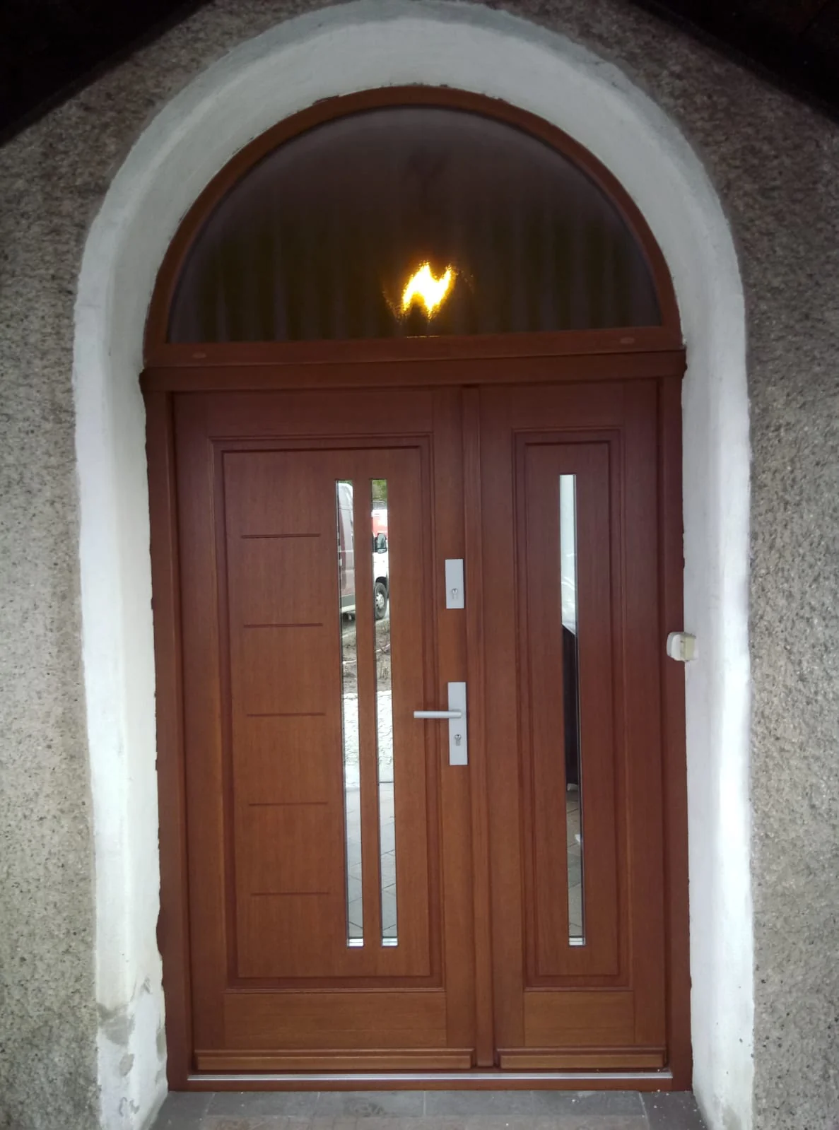 Brązowe drzwi wejściowe z łukowym naświetlem